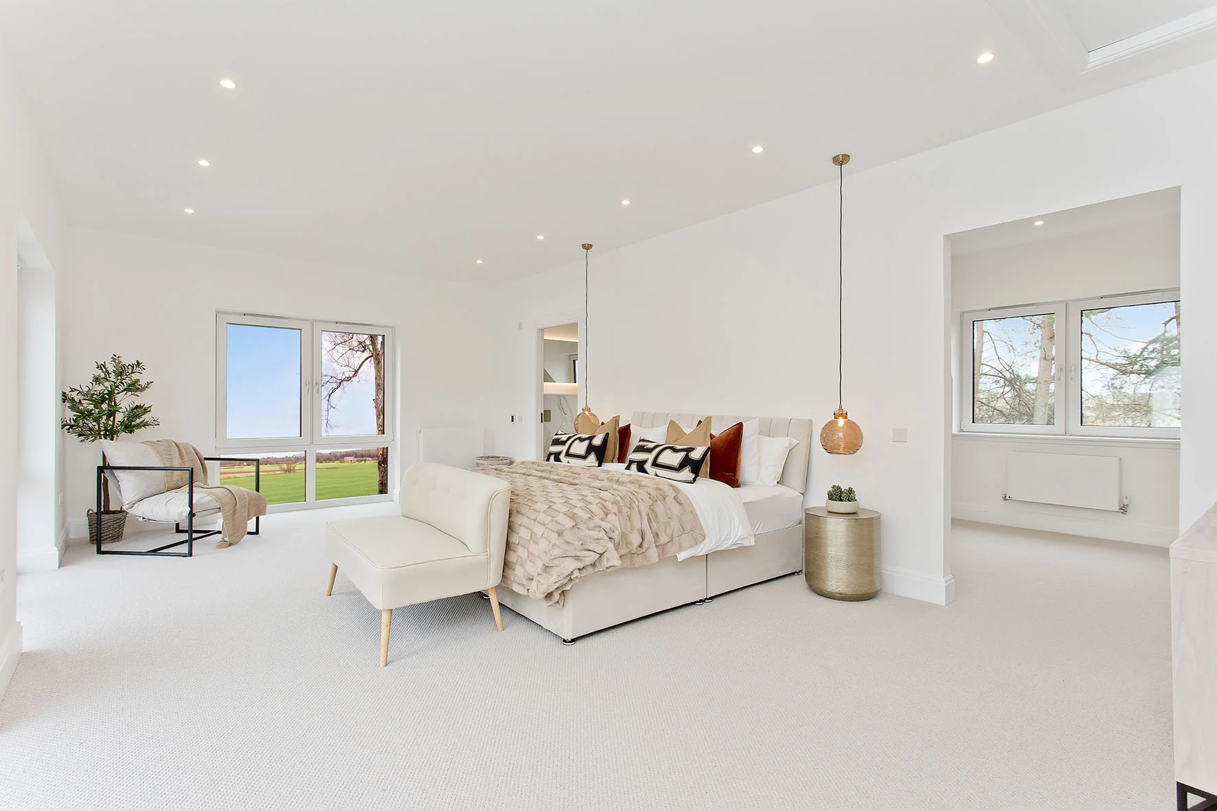 A generous principal bedroom with seating beside the windows